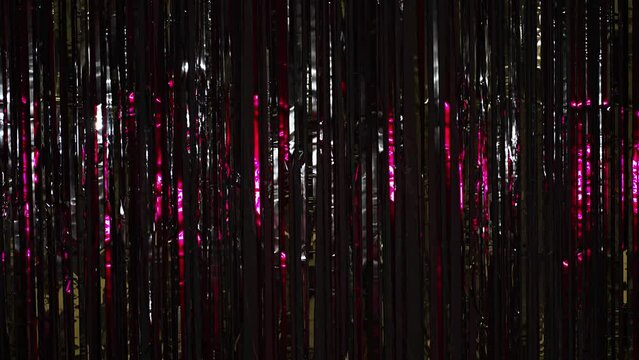 Silver rain from tinsel with pink light. Beautiful silver background with shiny silver glitter sparkles. Festive mood. Christmas or holiday theme. 