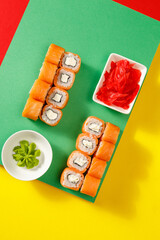 Set of sushi over colourful bright background served with soy sauce, wasabi and ginger. Colourful background. Assortment of sushi