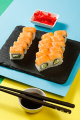 Set of sushi over colourful bright background served with soy sauce, wasabi and ginger. Colourful background. Assortment of sushi