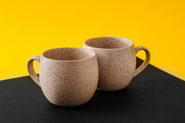 Two porcelain empty cups on a black and yellow background, copy space
