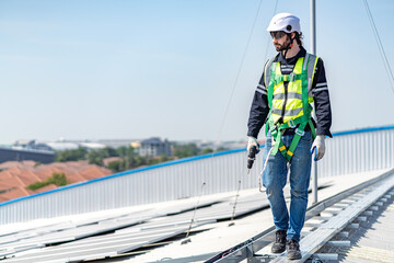 Male engineer installing or checking the working condition of solar panels on the roof or at the...