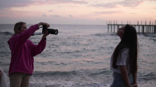 A female photographer takes a photo of a girl model in the evening by the sea. Turkey, Alanya