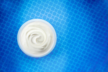 Face cream anti age moisturizing cosmetic on blue swimming pool background 