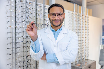 Naklejka na ściany i meble Smiling male consultant in lab coat selling eyeglasses