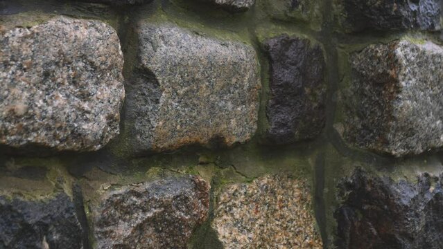 Ancient rock wall ruins made of grey stacked stones - close up tracking shot stone texture