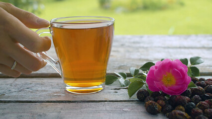 Hand putting a cup of rosehip tea on the table