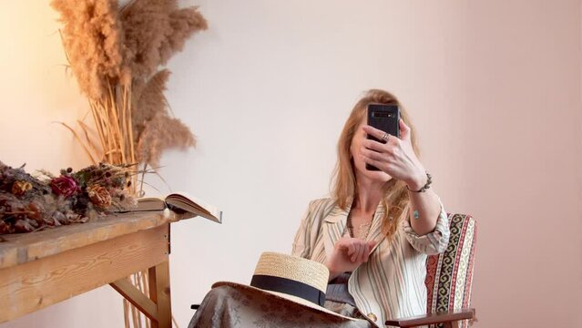 Rest of a woman psychologist with a smartphone in a boho interior among dry flowers. Unique concept for social networks