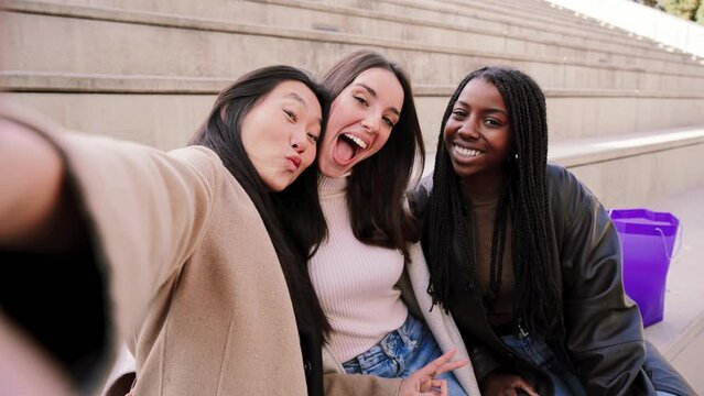 Happy group of multiracial young women taking a selfie portrait smiling at camera. Three diverse girls having fun outdoors. Best friends taking a photo. High quality photo