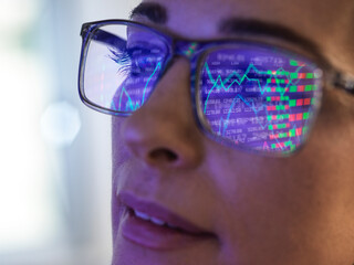Female expert in glasses looking at screen with financial data
