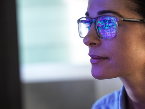 Female expert in glasses looking at screen with financial data