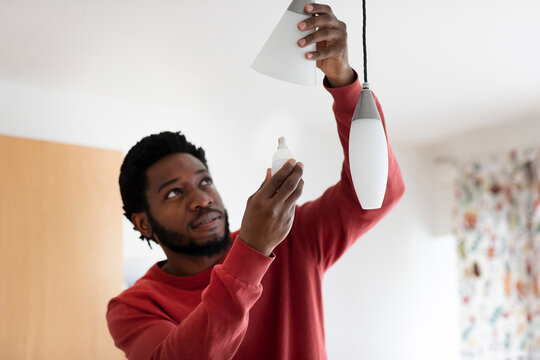 Young man changing bulb in electric light