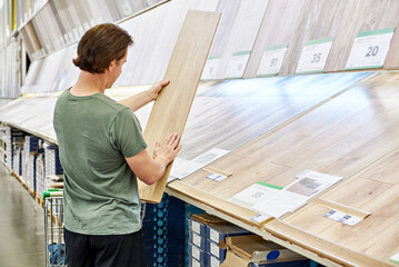 Man chooses floorboard laminate in store