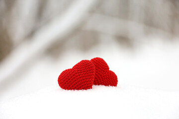 Two love hearts in snow on blurred forest background, Valentine's card. Background for romantic event, Christmas celebration or winter weather