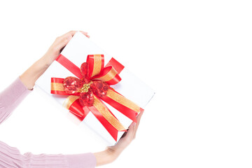 Female hands holding gift box wrapped with red ribbon isolated on white background with copy space. Woman hand holding gift box in christmas, new year, valentine day, birthday celebration concept.