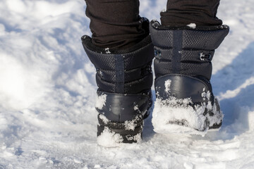 Legs of woman walking in winter park evening. Girl boots walking snow weather. Closeup of winter...