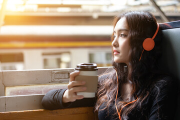 Charming beautiful traveler woman feeling relaxation and happy when gorgeous woman travel in public retro train she listening music and drinking delicious coffee in the morning.