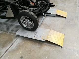 Rampe mit gelb lackiertem Riffelblech und Chassis eines alten englischen Sportwagen der...