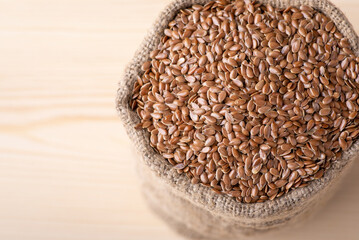 Linen grain in sack against wooden background. Fresh linen grain used for adding in bakery