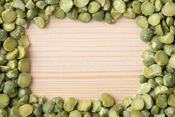 Frame made of green dry pea on wooden table. Close up of pea background on wooden table