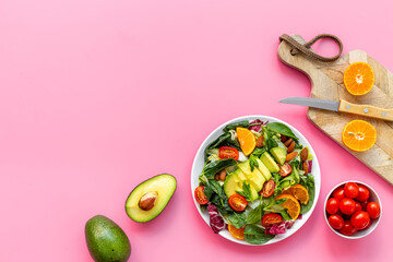 Cooking healthy green salad with avocado and tomatoes