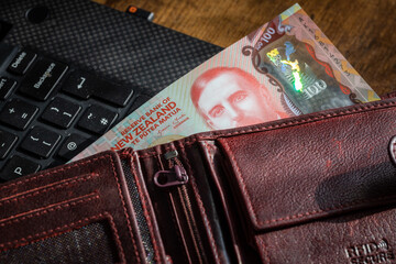 New Zealand money, a wallet full of dollars lying on a computer keyboard