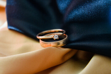 Wedding rings in gold and black satin fabric. Engagement. wedding photography. Gold paired rings crossed. Volumetric photography. Wedding. An offer of marriage. Diamond