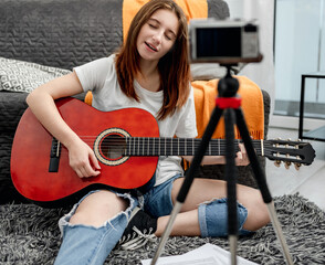Girl teenager with guitar recording streaning with camera