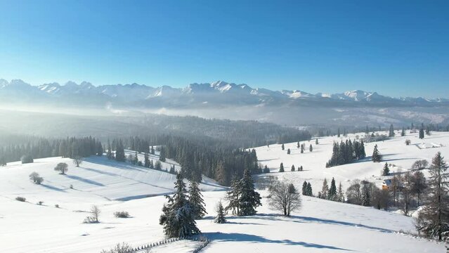 Epic alpine vista and white winter in the mountains. Aerial view of snow capped mountain landscape. Tatra high mountain range and magical unspoiled scenery with frozen spruce trees.