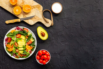 Cooking healthy green salad with avocado and tomatoes