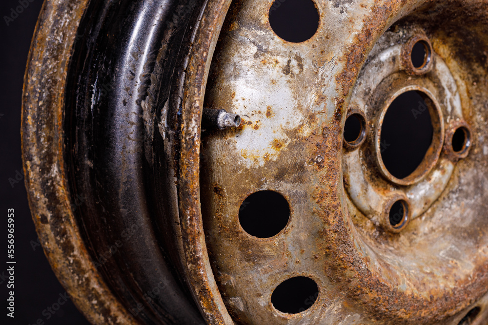 Poster old metal car rim with rust close-up on a black background