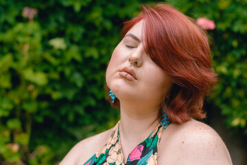young latina caucasian plus size model woman, outdoors with eyes closed, thinking and relaxed.