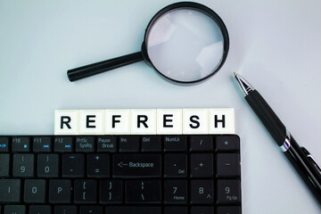 laptop keyboard, magnifying glass and pen with the word refresh. the concept of refreshing a computer or laptop