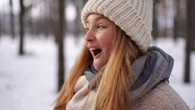 Excited smiling teen girl looking around talking standing in winter forest. Portrait of cheerful happy carefree Caucasian teenager enjoying vacations weekend in park outdoors. Slow motion
