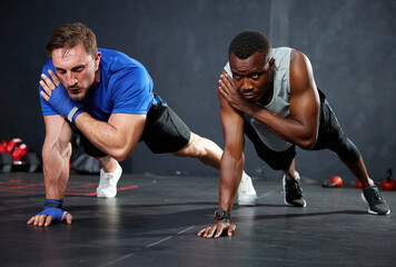 Fototapeta na wymiar athletics men doing push up and touching shoulder with on the gym floor