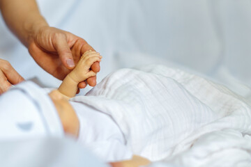 Close-up little hand of child and adult hands. The newborn baby sleeping after birth.