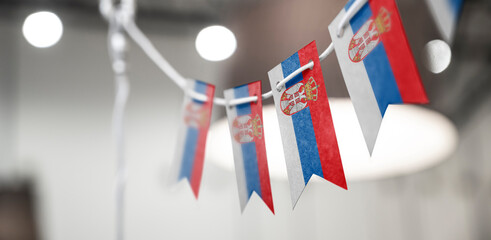 A garland of Serbia national flags on an abstract blurred background