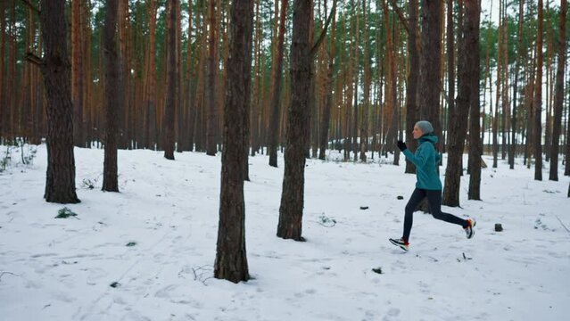sprinting fast exercising cardio workout in winter focused woman running in forest athlete training for marathon competition