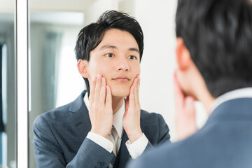 肌をチェックする若い日本人男性