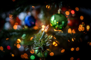 Lichter an einem Weihnachtsbaum. Im Hintergrund sind bunte Christbaumkugeln erkennbar. 