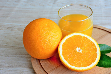 orange juice in drinking glass with half of orange isolated on cutting board, macro