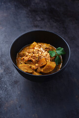 Traditional Indian vegetarian Madras curry stew with sweet potatoes and roasted cashew nuts served as close-up in design bowl with copy space