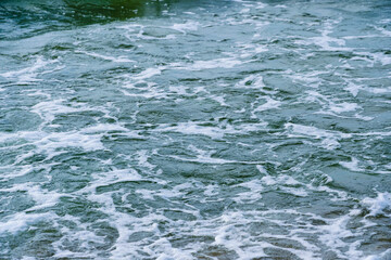 Surf wave with foam splashes on sea.
