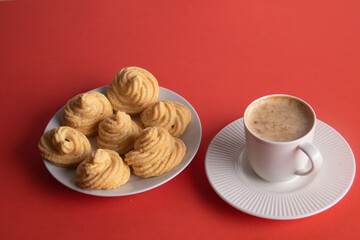 photo meringue cakes lying on a white plate and a white coffee cup with coffee