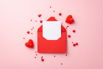 Valentine's Day concept. Top view photo of open red envelope with letter heart shaped candles and...