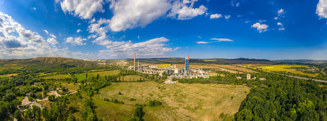 Naklejka na ściany i meble Panoramic view from a drone of an industrial factory. The industrial landscape of a cement factory.