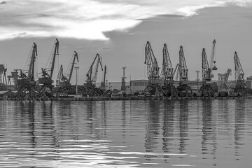 In the evening, the silhouette of port cranes. Ready to load containers from cargo ships.