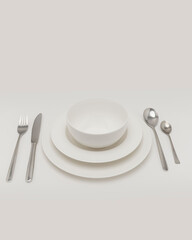 serving for lunch made of white dishes Stainless steel knife and fork and empty white dinner plate on a plain back background. No people.