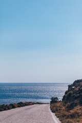 Winding roads of Tinos Island with crystal clear water of the Aegean Sea on Tinos island, Cyclades, Greece