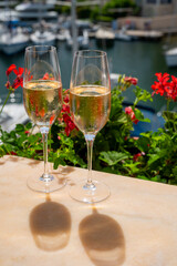Drinking of French brut champagne sparkling wine in glasses in yacht harbour of Port Grimaud near Saint-Tropez, French Riviera vacation, France