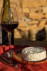 French wine and cheese pairing, glass of red beaujolais wine served with Saint-Félicien cow's milk cheese outdoor in Beaujolais winery near Lyon, France